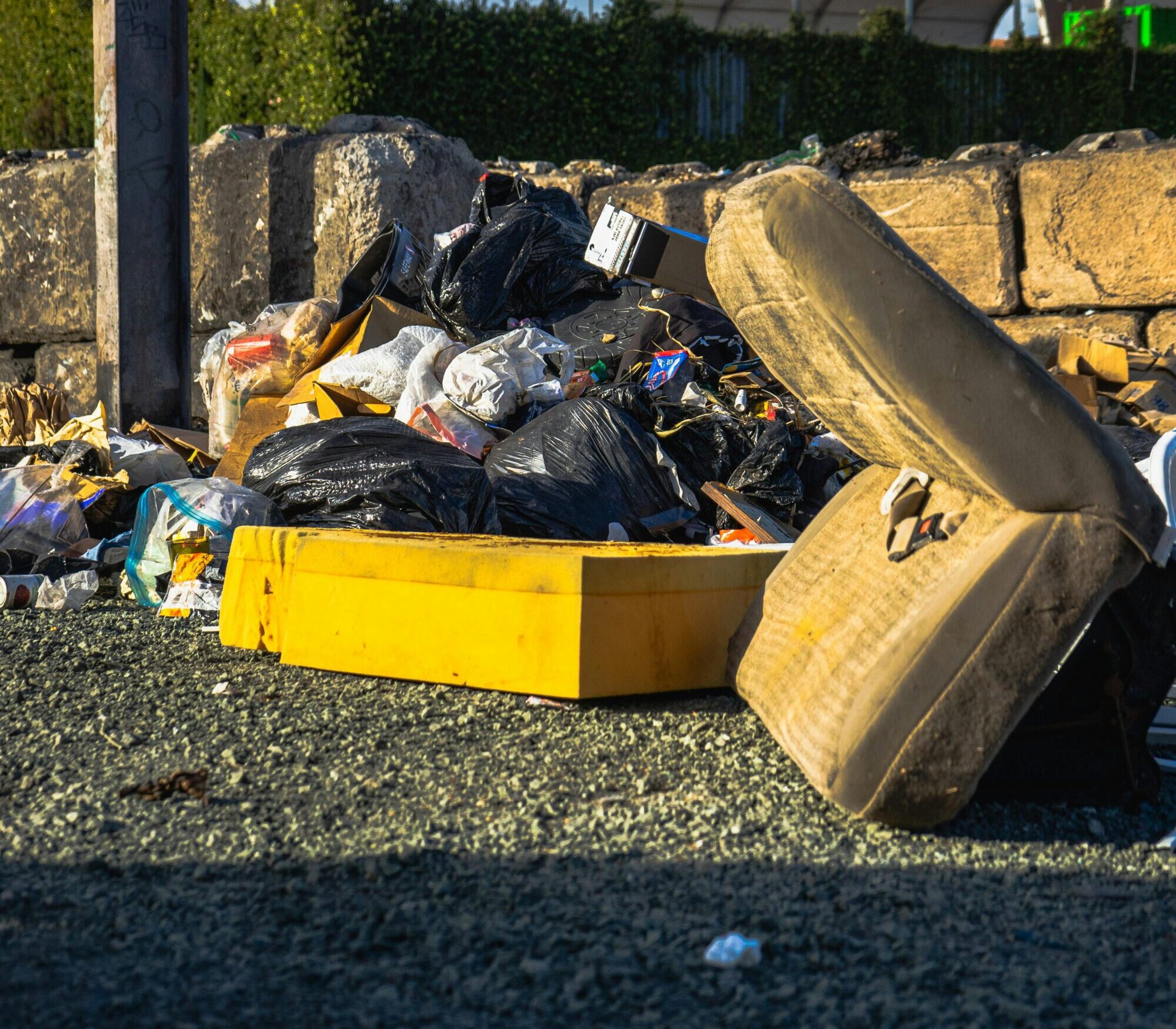 Outdoor scene of a garbage pile including a discarded mattress and various waste materials.